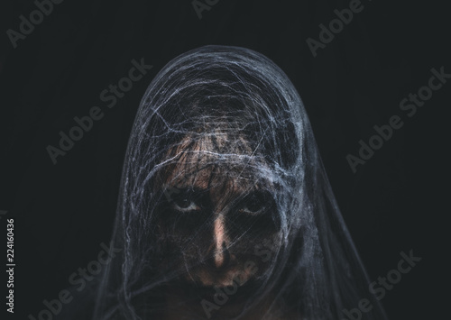 Creepy character covered with spiderweb on black background