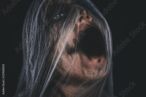 Screaming creepy character covered with spiderweb on black background