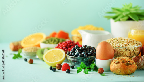 Healthy breakfast ingredients  food frame. Oat and corn flakes  eggs  nuts  fruits  berries  toast  milk  yogurt  orange  banana  peach on blue background. Top view  copy space. Flat lay