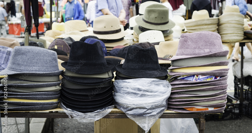 stand of a street market with hats and bonnets for sale.