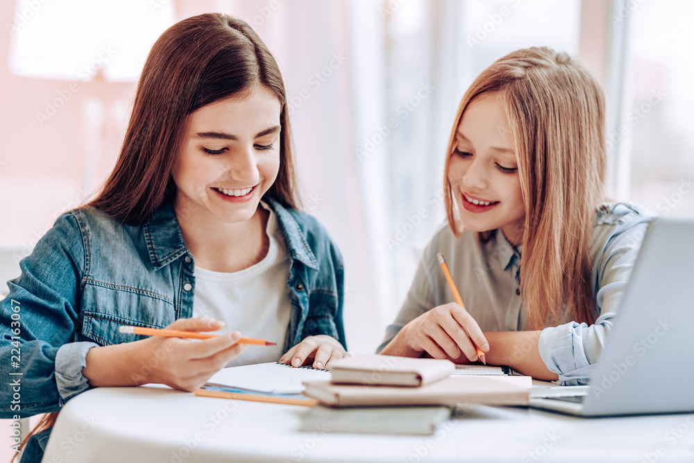 I understand. Pleased young females sitting at the table and preparing for lesson I understand. Pleased young females sitting at the table and preparing for lesson