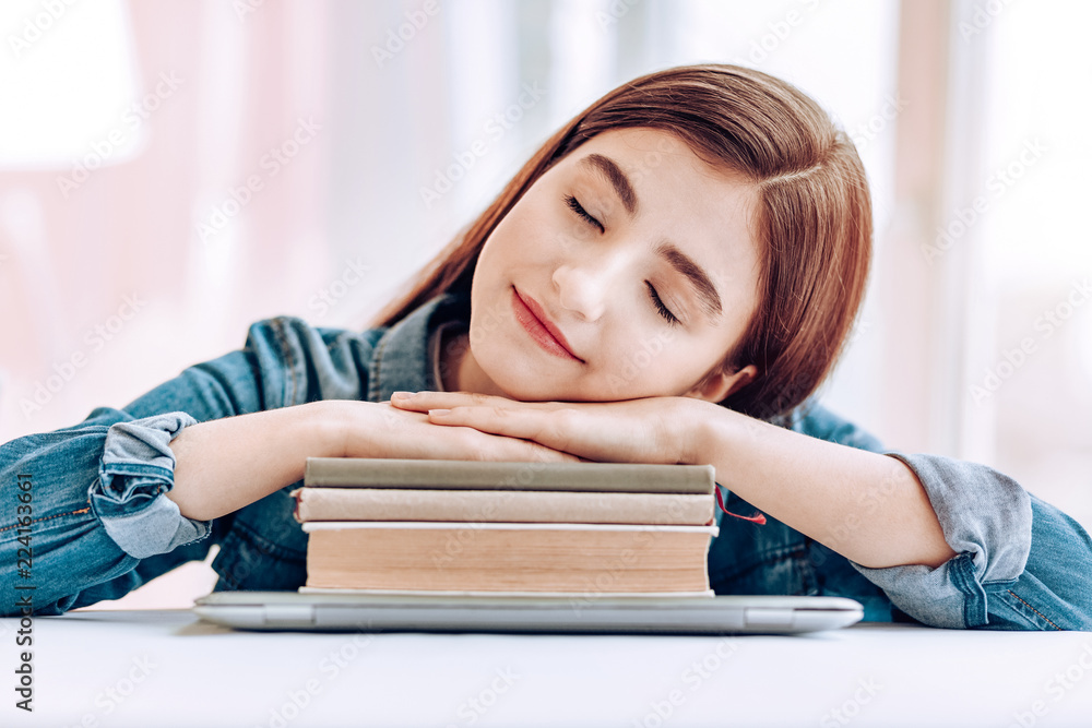 Sweet dreams. Charming brunette pupil keeping eyes closed while sleeping on books Sweet dreams. Charming brunette pupil keeping eyes closed while sleeping on books
