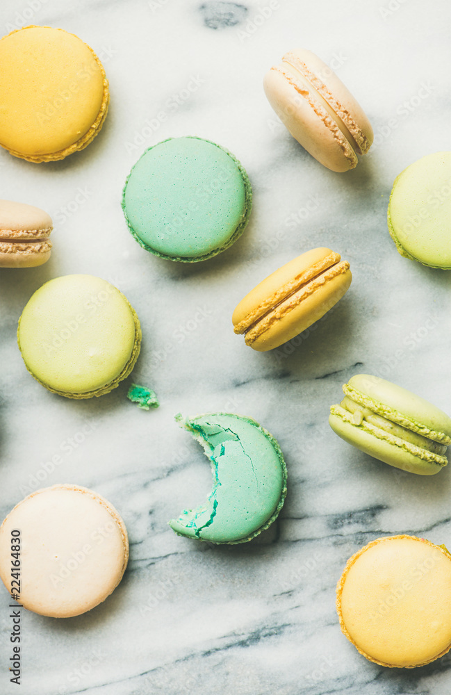 Flat-lay of sweet colorful French macaroon cookies over grey marble background, top view, vertical composition Flat-lay of sweet colorful French macaroon cookies over grey marble background, top view, vertical composition