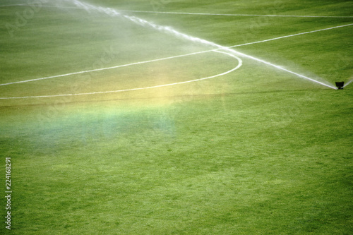 Regenbogen unterm Rasensprenger / Die grüne Rasenfläche eines Fußballfeldes mit einer Bewässerungsanlage die einen Regenbogen erzeugt... © ginton