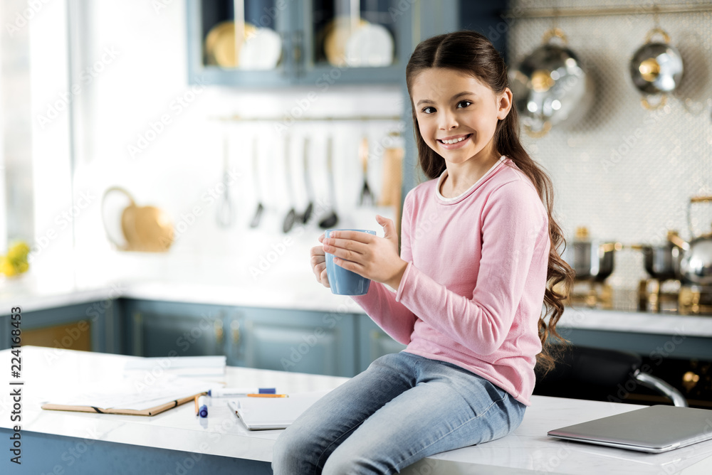 Break from study. Cheerful jovial girl holding cup and looking at camera Break from study. Cheerful jovial girl holding cup and looking at camera