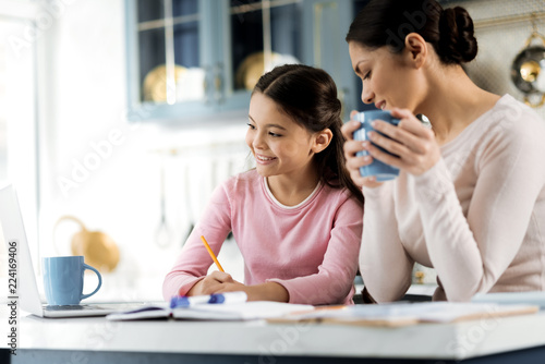 Helpful tips. Low angle of focused pretty girl studying and woman holding cup