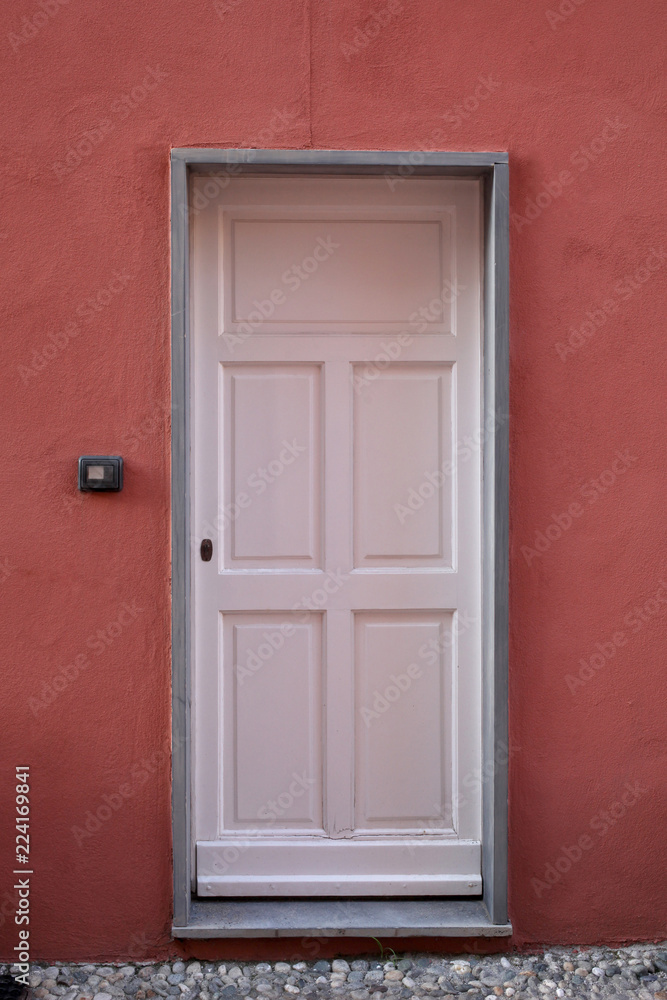 wooden white door on a red plaster wall
