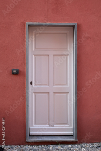 wooden white door on a red plaster wall