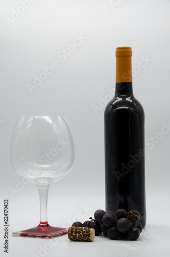bottle of wine with a cork, grapes and glass