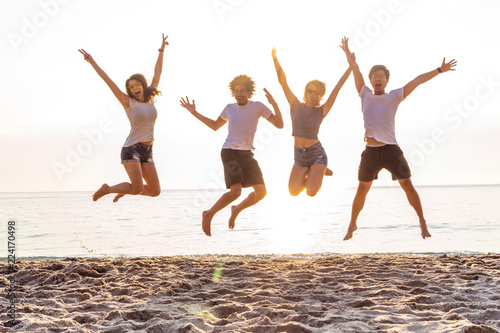 Group of friends together on the beach having fun. Happy young people jumping on the beach. Group of friends enjoying summer vacation on a beach.