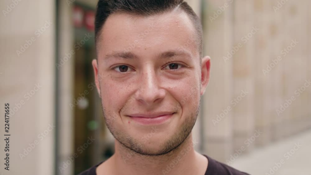 A young dark-haired man with a beard smiling in the city street. Close-up shot. Soft focus A young dark-haired man with a beard smiling in the city street. Close-up shot. Soft focus