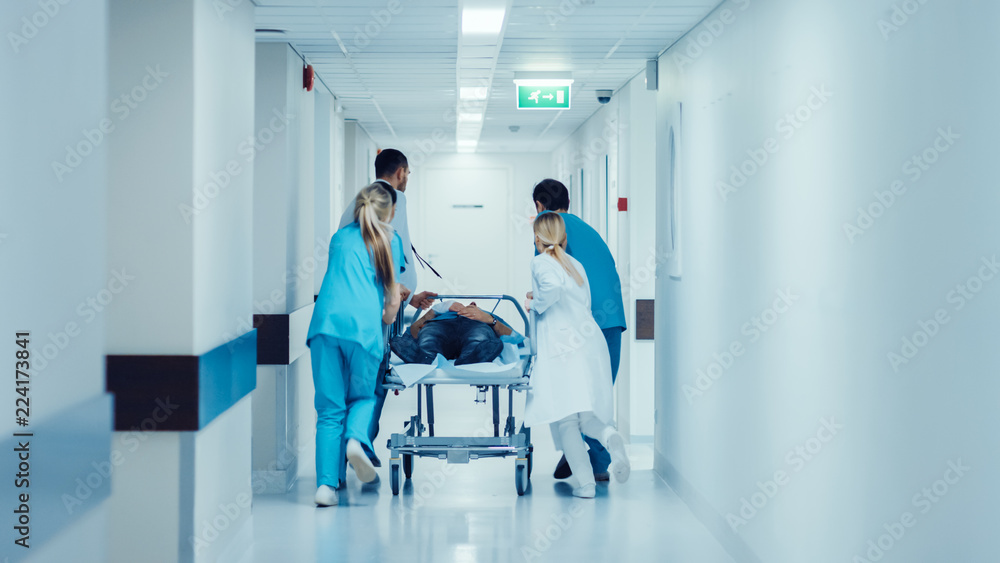 Emergency Department: Doctors, Nurses and Paramedics Push Gurney / Stretcher with Seriously Injured Patient towards the Operating Room. Bright Modern Hospital with Professional Staff Saving Lives.