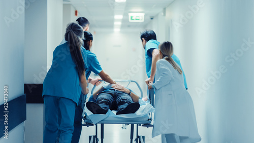 Obraz na plátně Emergency Department: Doctors, Nurses and Paramedics Push Gurney / Stretcher with Seriously Injured Patient towards the Operating Room