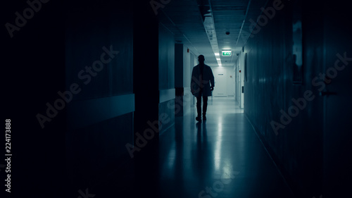 Medical Doctor Silhouette Walks in Dark Part of the Hospital Corridor.
