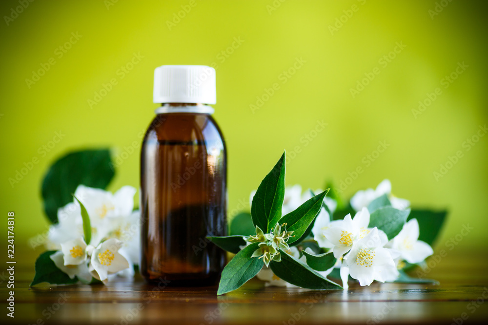 Essential aroma oil with jasmine on a green Essential aroma oil with jasmine on a green