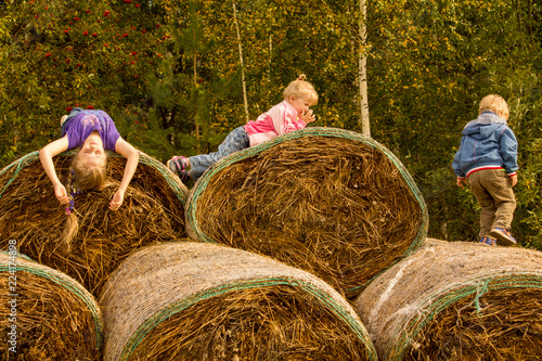 children play in the hay on a warm autumn day