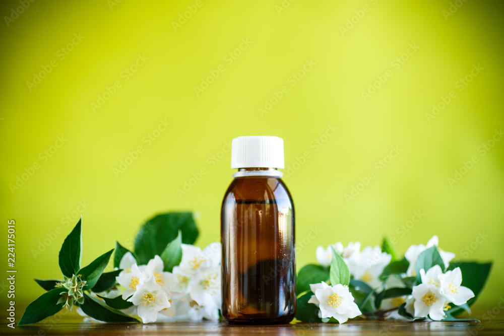 Essential aroma oil with jasmine on a green Essential aroma oil with jasmine on a green