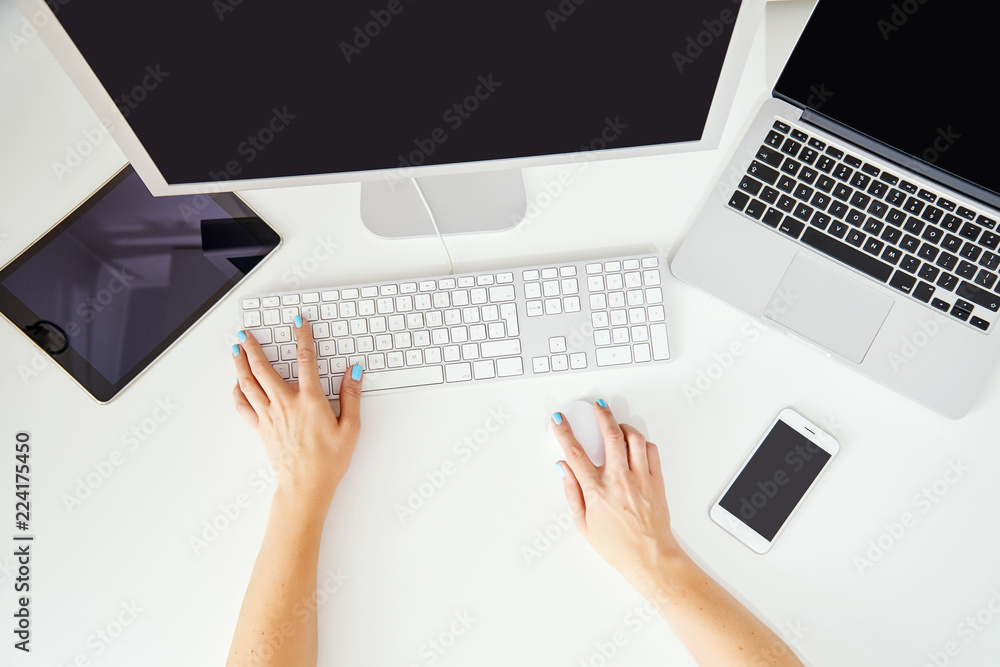top view on the woman's hand on the keyboard and computers in a home office top view on the woman's hand on the keyboard and computers in a home office