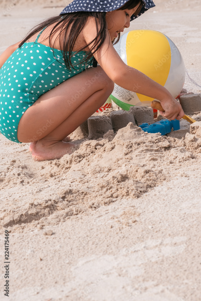 little asian girl playing with sand at the tropical beach in summer. little asian girl playing with sand at the tropical beach in summer.