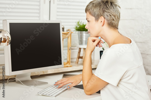 beautiful business woman in white dress sitting at desk and working on computer at home office