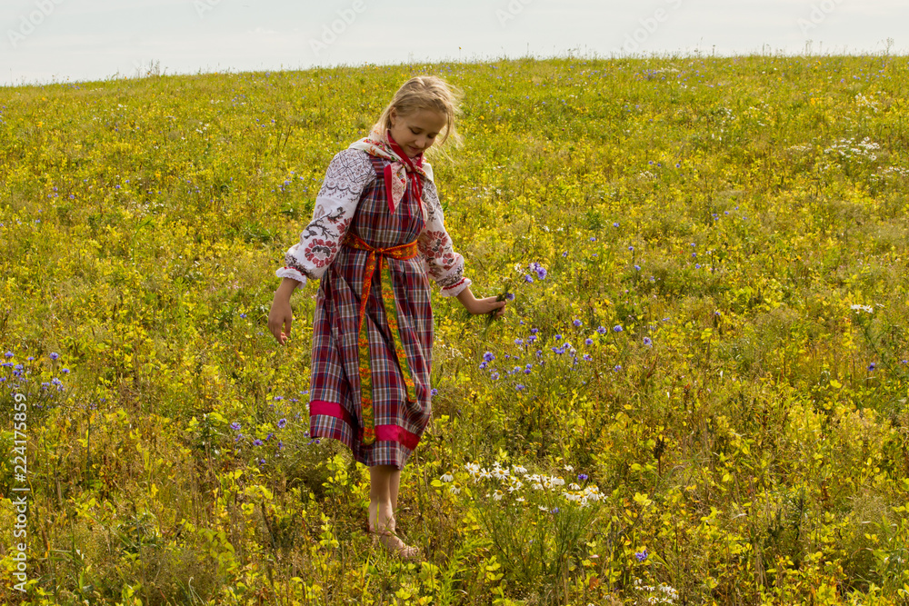 a girl in a Russian folk costume walks the field in a warm autumn afternoon