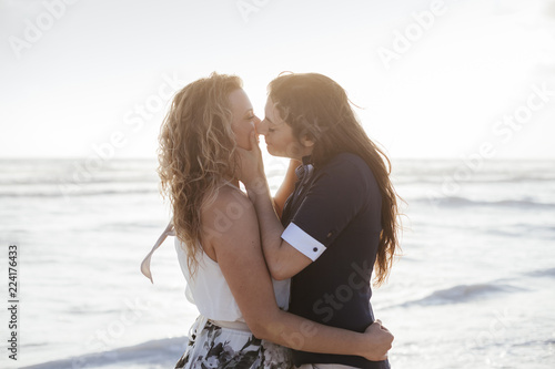 Fototapeta Young couple in love kissing on the deserted beach on a summer evening