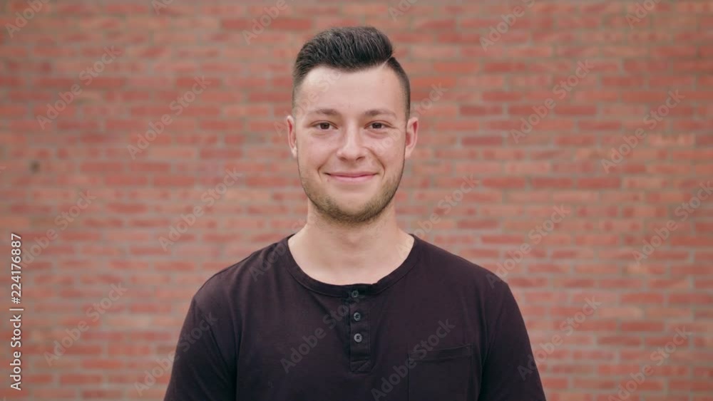 A happy smiling man with a small beard against a brick wall background. Close-up shot. Soft focus A happy smiling man with a small beard against a brick wall background. Close-up shot. Soft focus