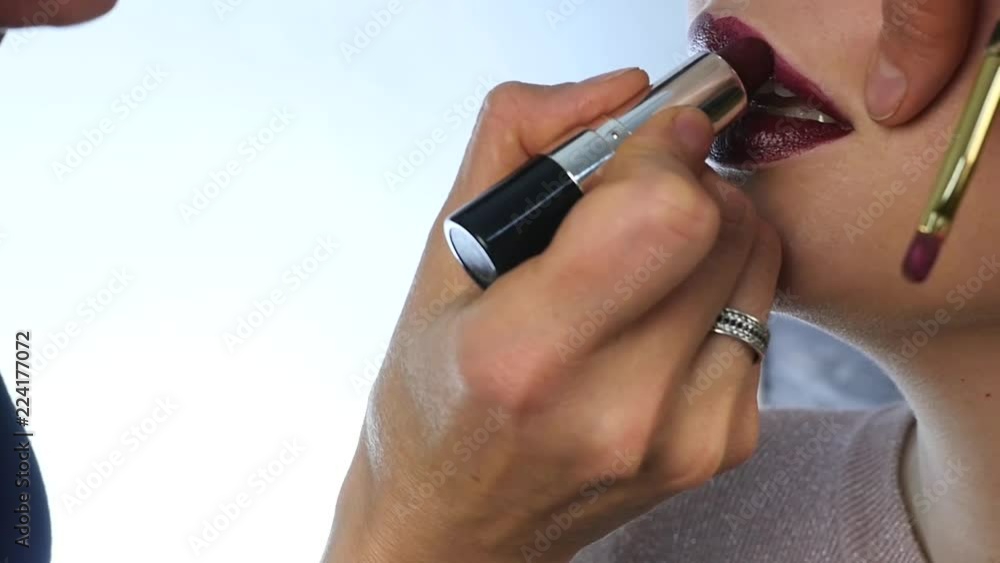 Professional make-up: Red lipstick on lips of seductive young model. slow motion Professional make-up: Red lipstick on lips of seductive young model. slow motion