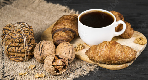 coffee with croissants and broken walnuts on the table