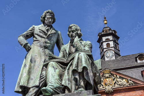 Germany  Hanau  National memorial statue of famous Grimm Brothers in the city center of the German town with town hall and blue sky in background - concept culture fairy tales art travel history