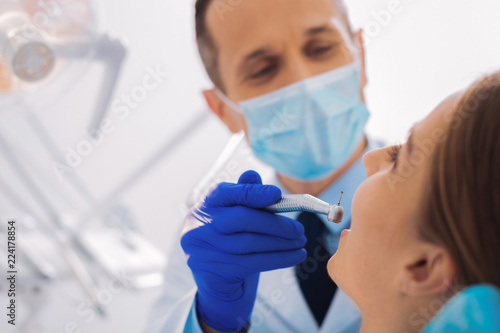 Final procedure. Calm attentive dentist looking careful while finishing curing his patient