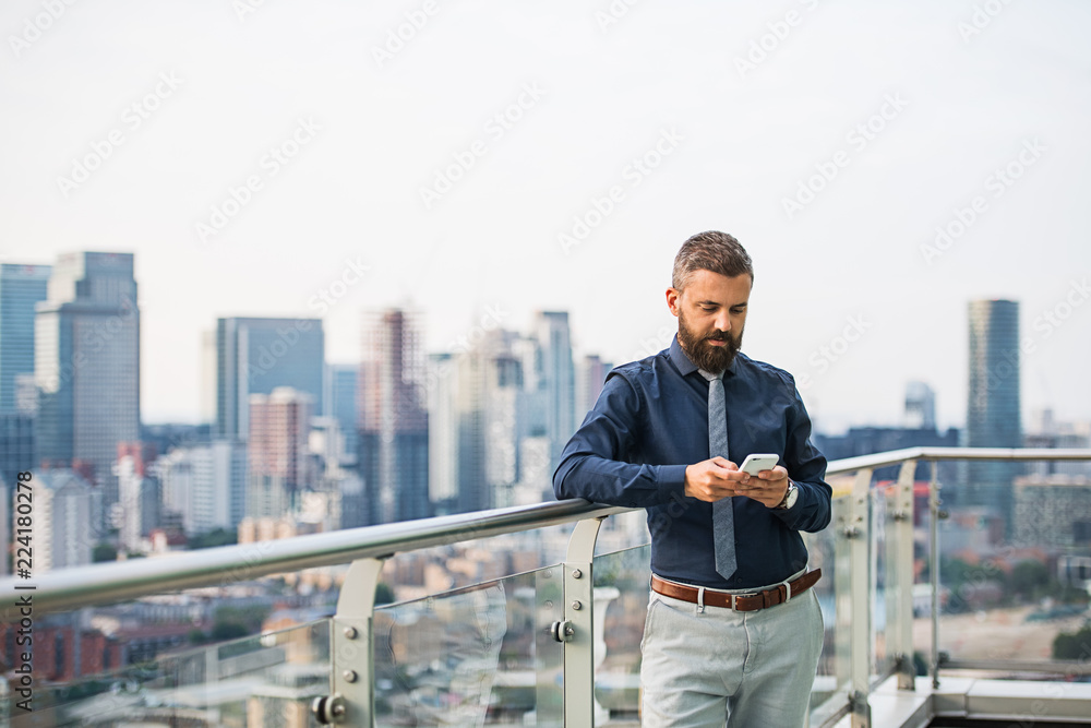Φωτογραφία A portrait of businessman with smartphone standing against London view panorama