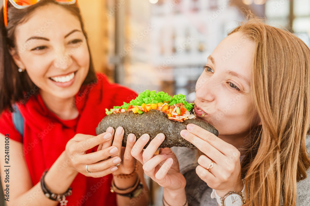 Cheerful multiracial friends eating sandwich and having fun in a cafe Cheerful multiracial friends eating sandwich and having fun in a cafe