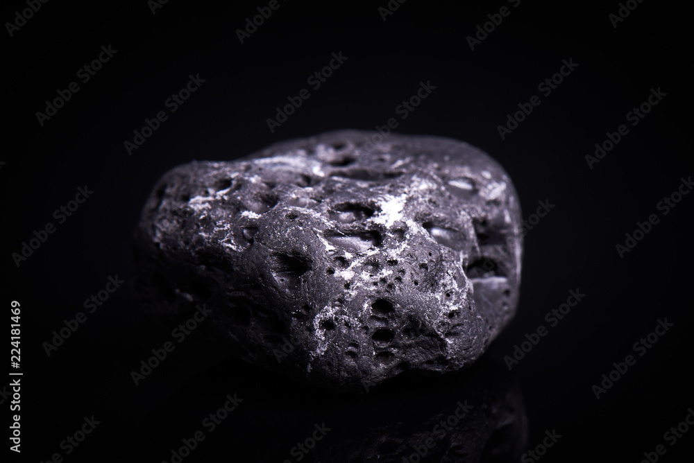 Black porous basalt stone on a black background Black porous basalt stone on a black background