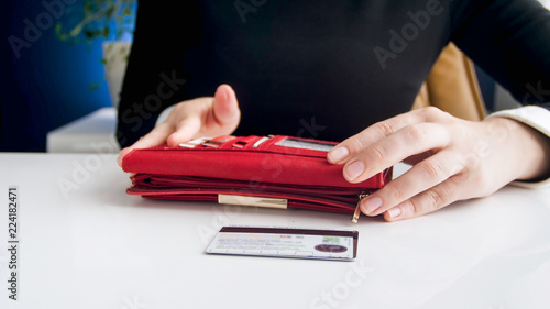 Closeup image of young businesswoman taking credit cards out of red leather wallet