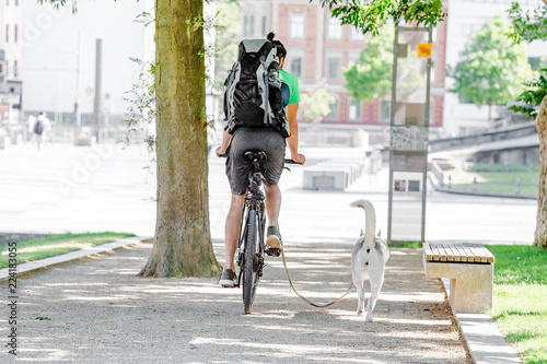 a man riding his bicycle with running dog