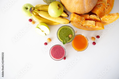 Autumnal vegetable and fruit smoothies on a white background next to pumpkin, spinach, banana, raspberries and apples. Diet, Detox and Vegetarian Food. Top view, flat lay. Copy space