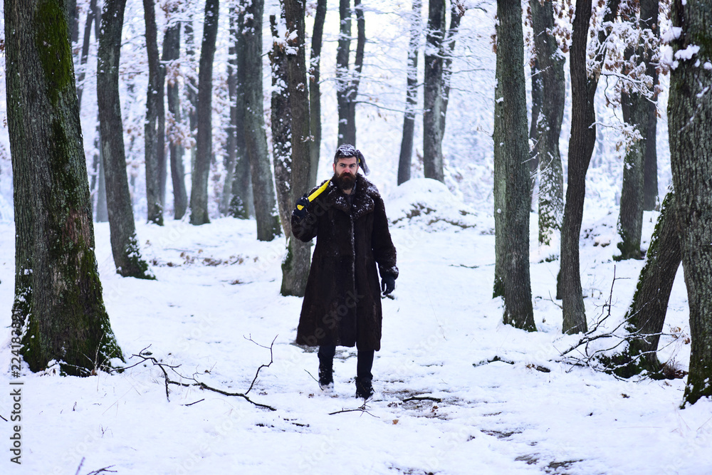 Frozen woodsman concept. Man in fur coat walking in forest.