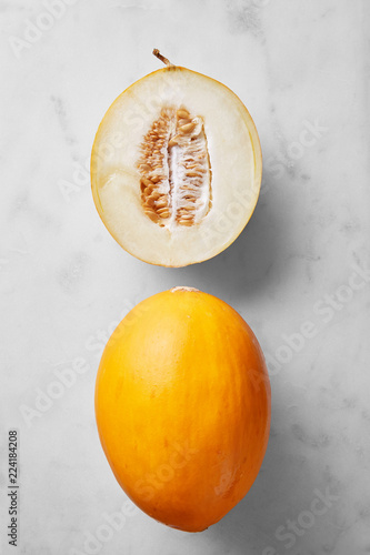 Mellon fruit half and whole isolated on a marble background viewed from above. Top view