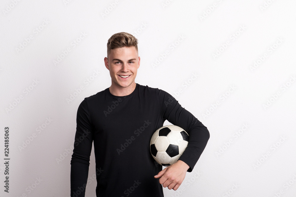 Portrait of a young man with football ball in a studio. Copy space. Portrait of a young man with football ball in a studio. Copy space.