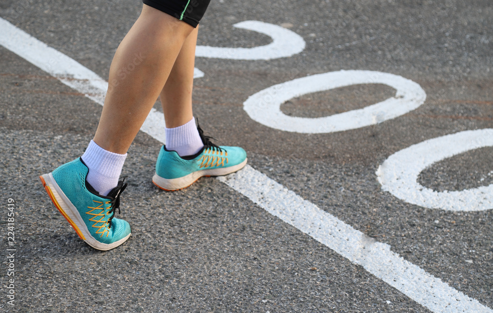 Closeup of woman' s feet at the line on jogging tract in the evening of sunny day