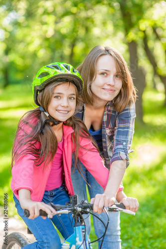 portrait of mother and daughter, learning to ride a bicycle