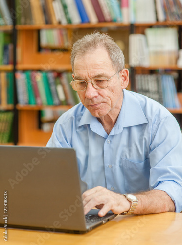 Senior man using laptop in library