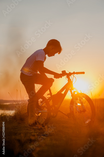 Fototapeta Naklejka Na Ścianę i Meble -  Young boy with bike at sunset
