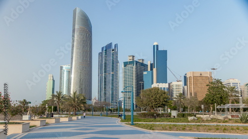 Corniche boulevard beach park along the coastline in Abu Dhabi timelapse with skyscrapers on background. © neiezhmakov