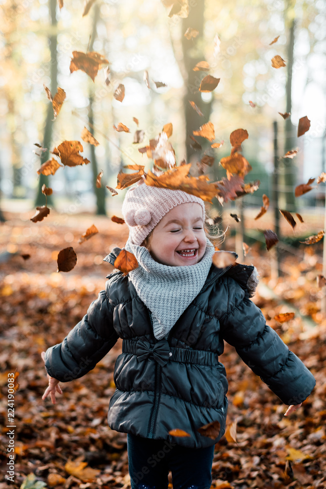 child is playing with leaves that have fallen from the tree child is playing with leaves that have fallen from the tree