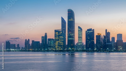 Abu Dhabi city skyline with skyscrapers before sunrise with water reflection night to day timelapse © neiezhmakov