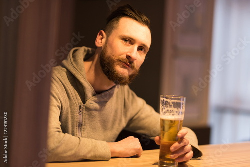 A handsome young hipster man drinking a beer at the bar.