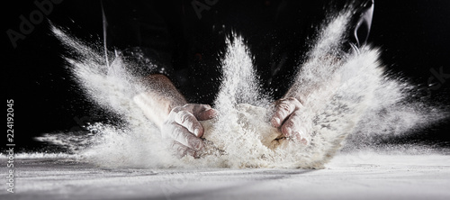 Foto Flour flying into air as chef slams dough on table