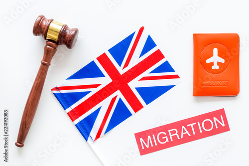 Immigration to Britain concept. Text immigration near passport cover and british flag, hammer on white background top view